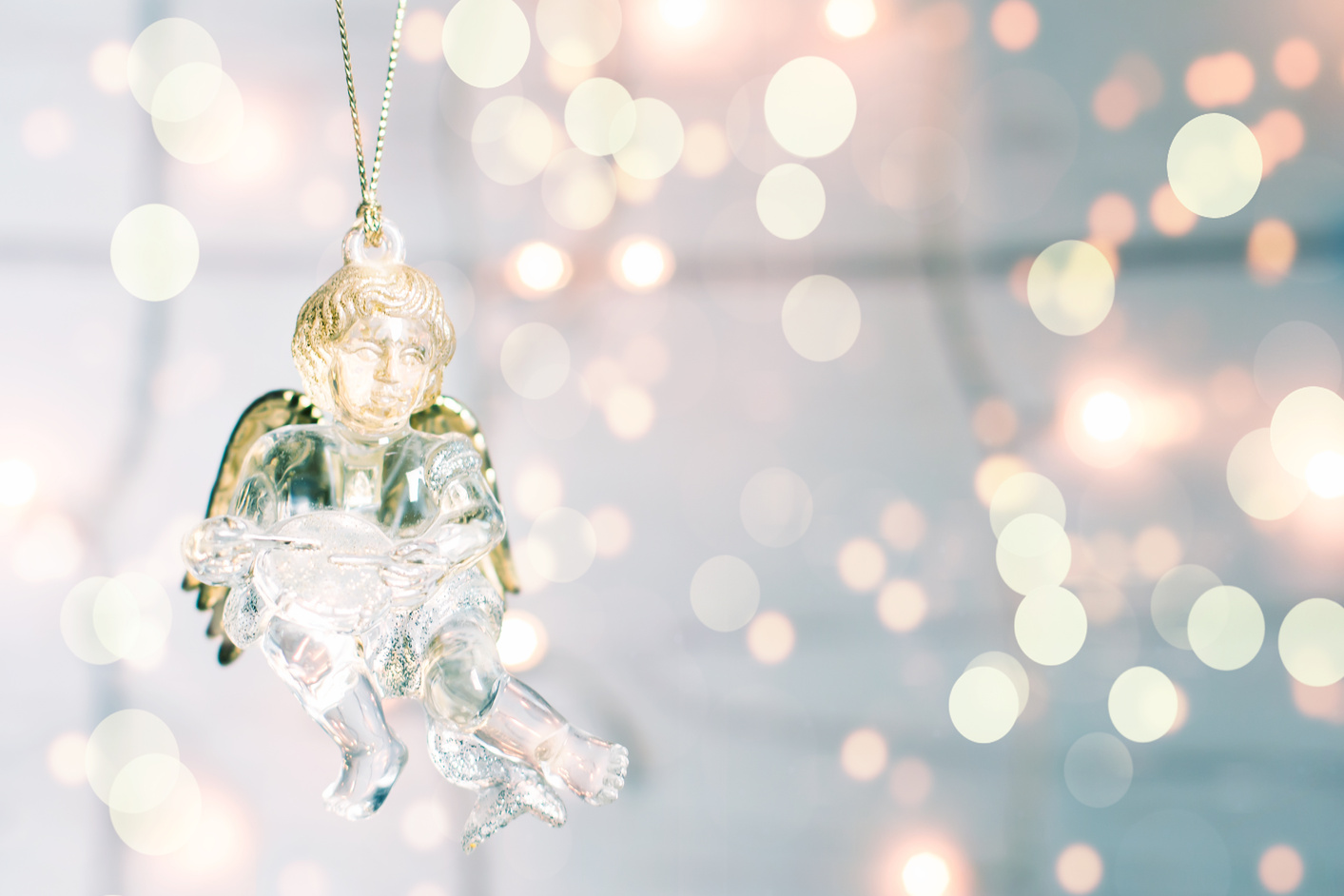 Glass toy Christmas Angel on a golgen bokeh background